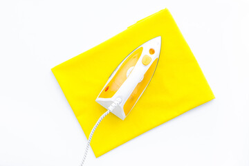 Yellow iron with clean linen on ironing board. Top view, copy space