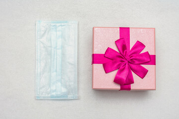 Medical mask and pink gift, copy space, top view