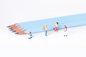 Closeup shot of little figurines of students next to pencils