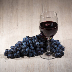 ripe wonderful red grapes and red wine in a glass on the table