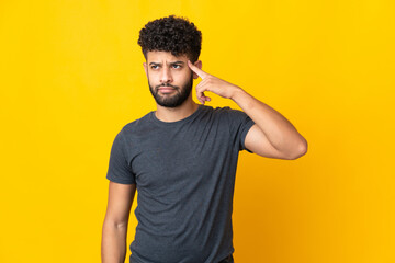 Young Moroccan man isolated on yellow background making the gesture of madness putting finger on the head