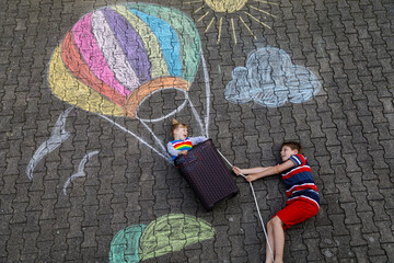 Happy little toddler girl and kid boy flying in hot air balloon painted with colorful chalks in...