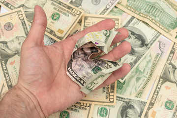 Hand with a crumpled five-dollar bill, dollar bills in the background, man's hand, closeup