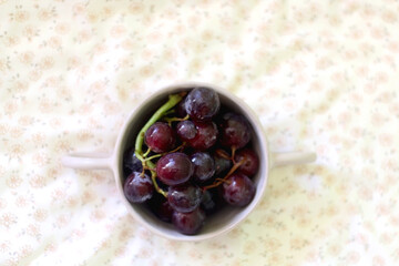 Bowl of grapes on a bed. Top view.