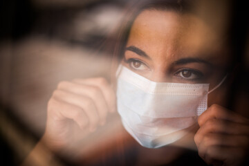 Woman wearing a surgical mask by a window