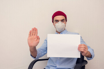 Man shows a stop sign with his palm, man in a respiratory at home on self-isolation, portrait, copy...