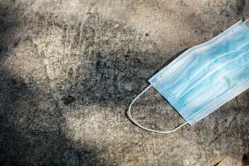 Medical protection mask lost on the ground was used. Disposable mask lying on the street. Incorrectly discarding the used face mask
