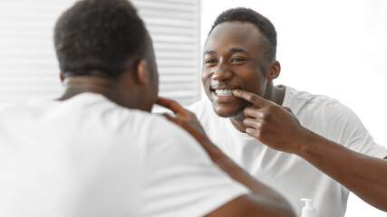African Man Checking Teeth Smiling To Mirror Standing In Bathroom