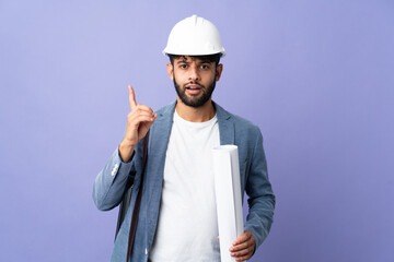 Young architect Moroccan man with helmet and holding blueprints over isolated background intending to realizes the solution while lifting a finger up