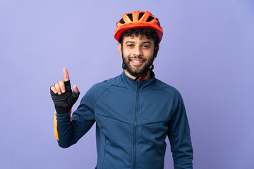 Young Moroccan cyclist man isolated on purple background showing and lifting a finger in sign of the best