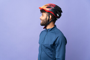 Young Moroccan cyclist man isolated on purple background laughing in lateral position