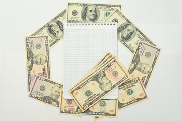 Dollars USA of different denominations and notebook, top view, copy space