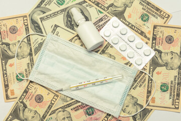 USA Dollars bills, medical mask, spray nasal and thermometer, top view