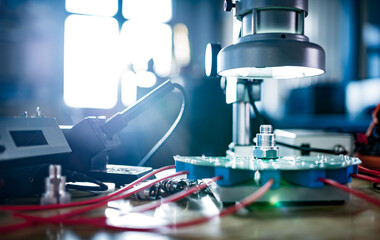 Modern microscope, connectors component and large green microcircuit in workshop laboratory