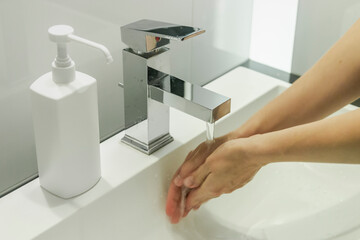 Modern bathroom with sink and soap/disinfection fluid (mock-up). Cleaning hands in washbasin.