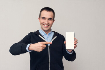 Handsome person points to the smartphone, white background, copy space