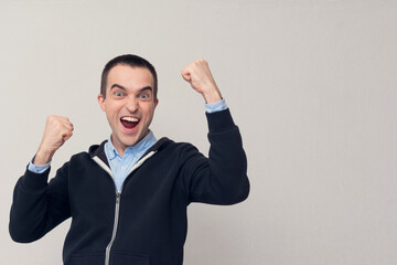 Happy young man shouts: Hooray! Yes! White background, copy space