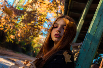 Beautiful redhead girl posing in the train stop in autumn.