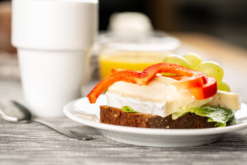 Hotel breakfast with coffee, sandwich with brie and grape and orange juice