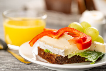 Hotel breakfast with sandwich with brie and grape, boiled egg and orange juice