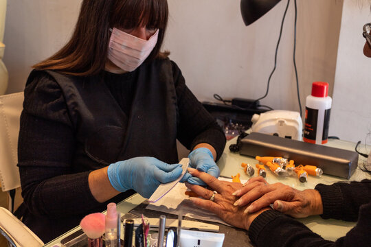 Beautiful women manicurist working with her client with mask.