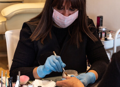 Beautiful women manicurist working with her client with mask.