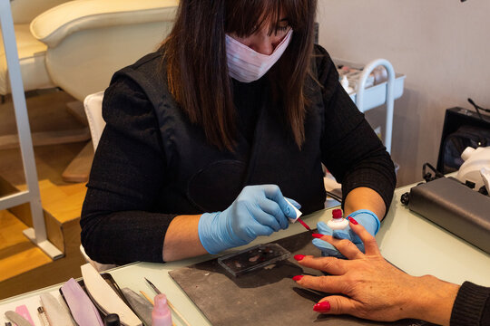 Beautiful women manicurist working with her client with mask.