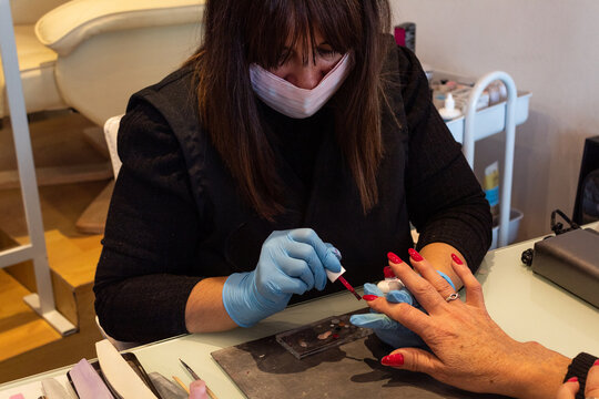 Beautiful women manicurist working with her client with mask.