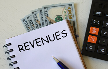REVENUES word in a notebook against the background of calculitar and banknotes