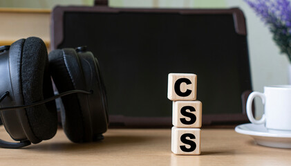 CSS -acronum on cubes on the background of the tablet, headphones and a white cup