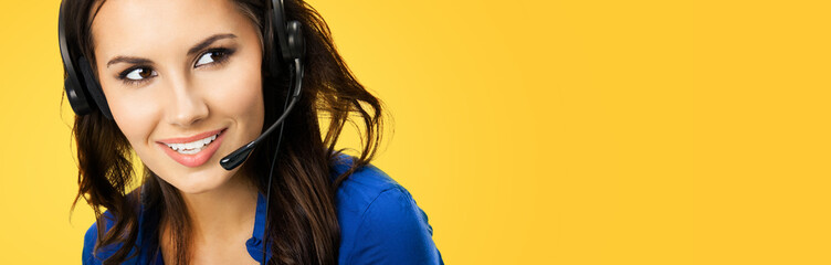 Call center service. Customer support phone sales operator with copy space for some text or slogan, over yellow orange color background. Beautiful woman in headset. Studio portrait image.
