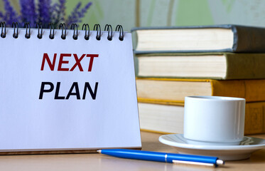 NEXT PLAN - a words in a notebook against the background of old books with a pen