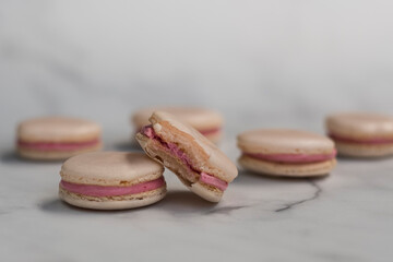 Pink macarons scattered on white background. Selective focus on cookie with bite taken out. 