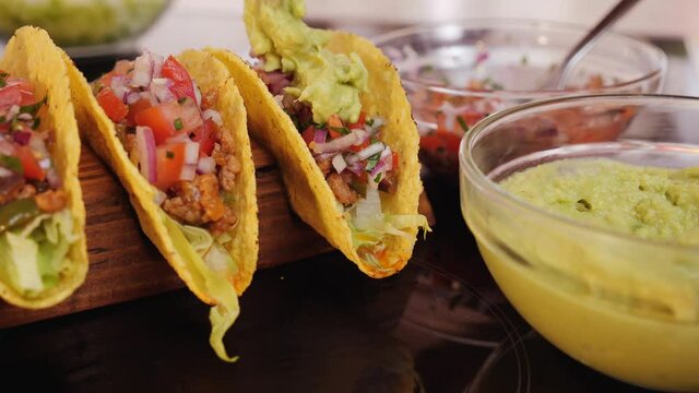 Woman hand prepare tacos - adding the guacamole topping, static camera, close up. Phases of making delicious taco.