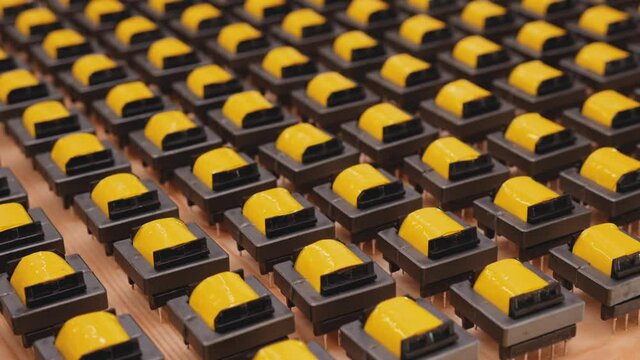 Electronic component manufacturing - camera slide over many transformer coils in factory, production of electronics and technology concept, close up