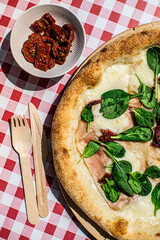 Italian pizza with cheese, spinach and dried tomatoes.