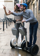 Fototapeta na wymiar young couple guy and girl walking on segway in streets of european city