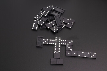 The black dominoes were laid out on a dark table.