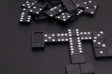 The black dominoes were laid out on a dark table.
