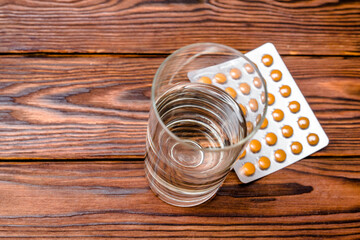A package of orange tablets is placed on a brown background
