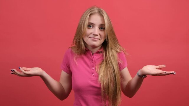 Close up of a clueless girl that is feeling confused about question, smiling over red background.