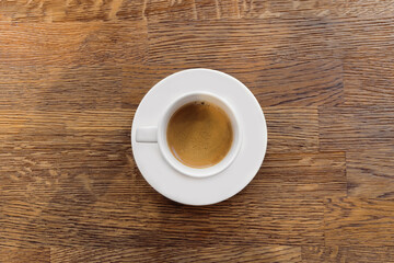White cup of coffee on wooden table as a background.