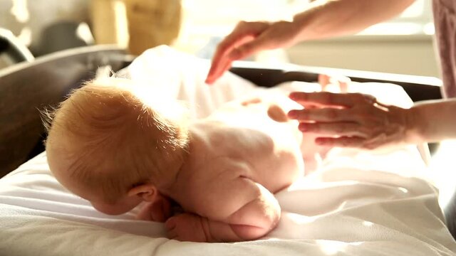 Newborn Baby Lying On The Bed On His Stomach And His Mother Patting Him 