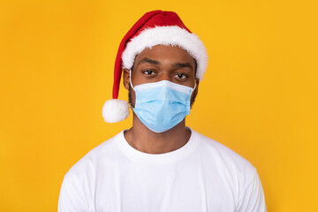 African Man Wearing Mask And Christmas Santa Hat, Yellow Background