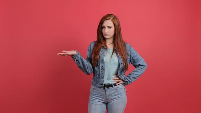 Caucasian young woman isolated over red background is unhappy, she raises her hand and gestures showing that he does not understand anything