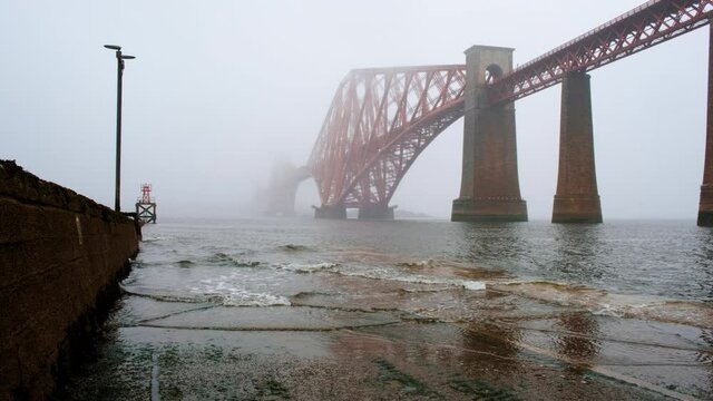 Wide view of the Forth Bridge enshrouded in mist seen from North Queensferry in Fife, a cantilever railway bridge across the Firth of Forth and a symbol of Scotland, UK