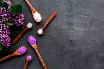 Fototapeta na wymiar Pattern of spa sea salt in spoons with lilac flowers. Above view