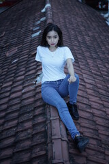 The blonde girl sits on the roof tile in a style wearing a white t-shirt. female t-shirt models for mockups and templates.