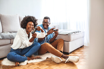 Playing video games. Who will win? Excited funny friends, playing video games at home, sitting on sofa and enjoying themselves. They have great weekend in nice company indoors © Dragana Gordic