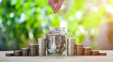 Hand putting coin in a jar and stacking of coins for saving concept investment mortgage fund...